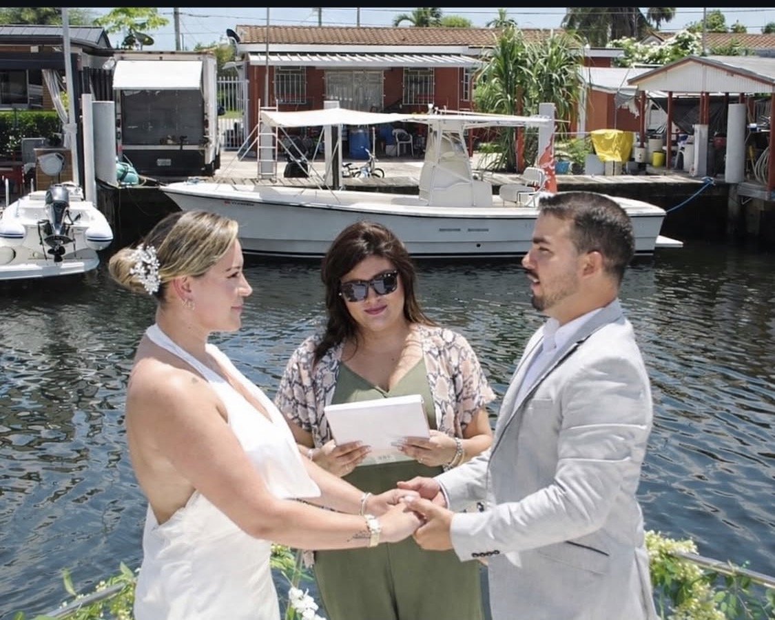 Una pareja tomada de las manos durante una ceremonia junto al agua